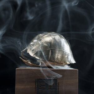 A metal turtle-shaped incense burner with engraved surface.